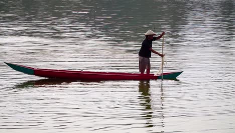 unknown fisherman searching for fish using traditional boat and net