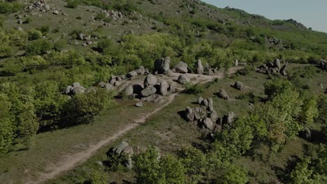 Aerial-tracking-shot-eroded-granite-monoliths,-old-mountains-spring-time,-sunny-day