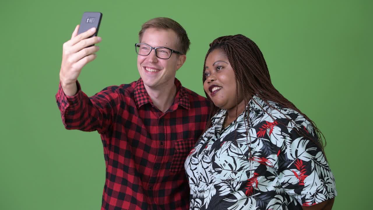 Donna africana in sovrappeso e giovane uomo scandinavo insieme su sfondo verde