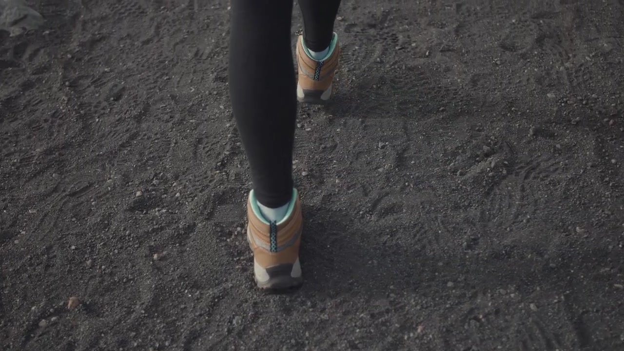 Piedi di escursionista con gli scarponi che camminano su un sentiero di ghiaia scura