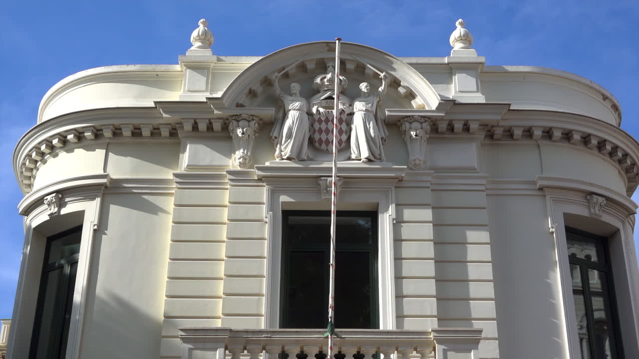 Monaco City, Monaco - July 4, 2025: Close up of the Principality's coat of arms with two monks and the motto carved on the facade of the Palace of Justice. Translation: "God willing"