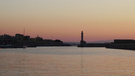 Hermosa-Vista-De-La-Puesta-De-Sol-Sobre-El-Mar-Egeo-En-Chania,-Antiguo-Puerto-Veneciano-Con-Faro-Histórico-Durante-La-Noche-De-Verano,-Lugar-Turístico-En-Grecia