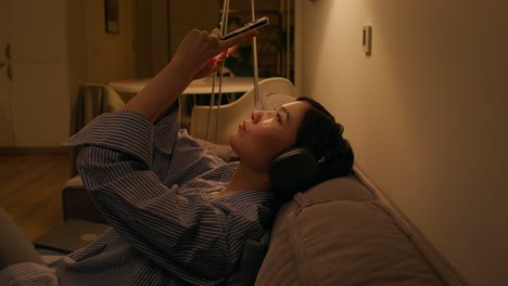 woman relaxing on couch with headphones and phone