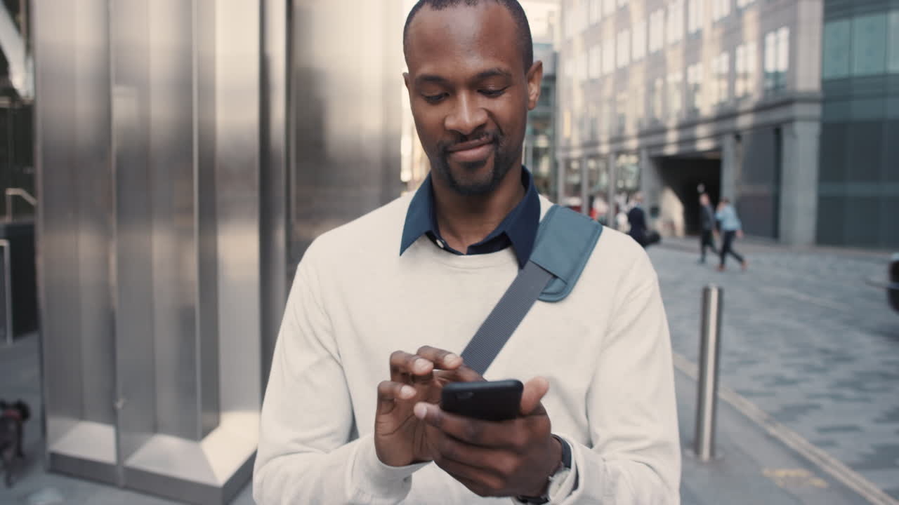 African American businessman walking through city using smart phone
