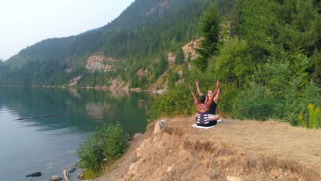 friends performing yoga near lakeside 4k