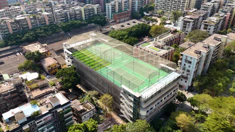 a rooftop sports complex in guangzhou, china, with a football field and tennis courts. a unique blend of urban architecture and recreational facilities in the heart of the city.