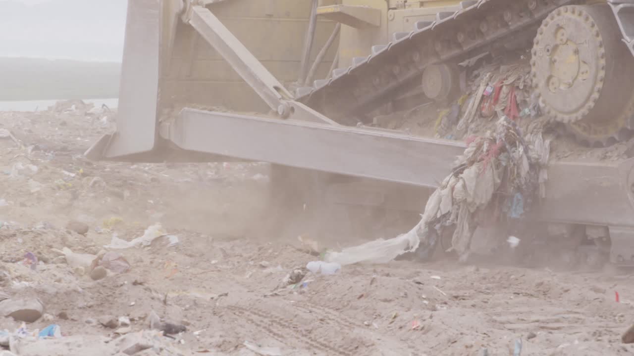 vehículos que limpian la basura apilada en un vertedero lleno de basura