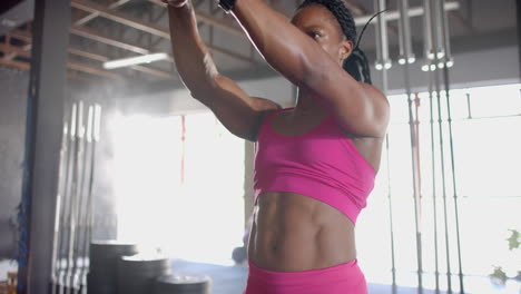 lifting kettlebell, woman in gym focusing on strength training workout