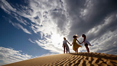 friends silhouetted on a sand dune with dramatic sky