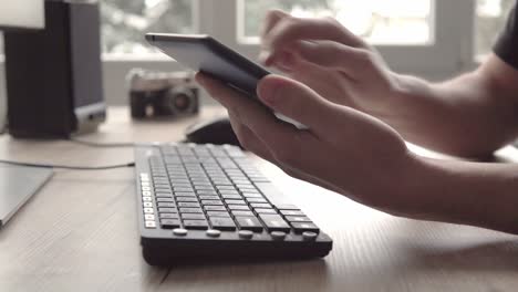 young man using tablet while sitting computer keyboard and mouse. freelancer photographer working and using tablet for communication with clients.