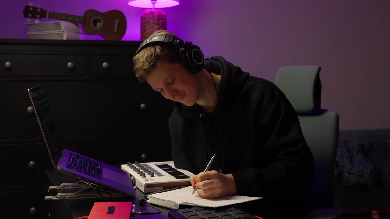 Male musician sits at workstation refining track layers with slow steady workflow in warm-lit home studio
