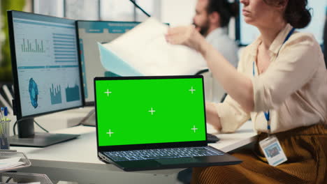 corporate staff uses dual monitors to analyze charts with mockup on laptop