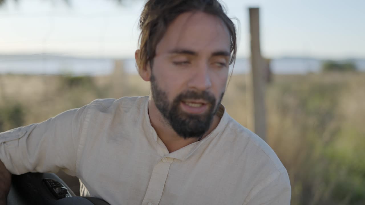 Man playing acoustic guitar on the beach at sunset