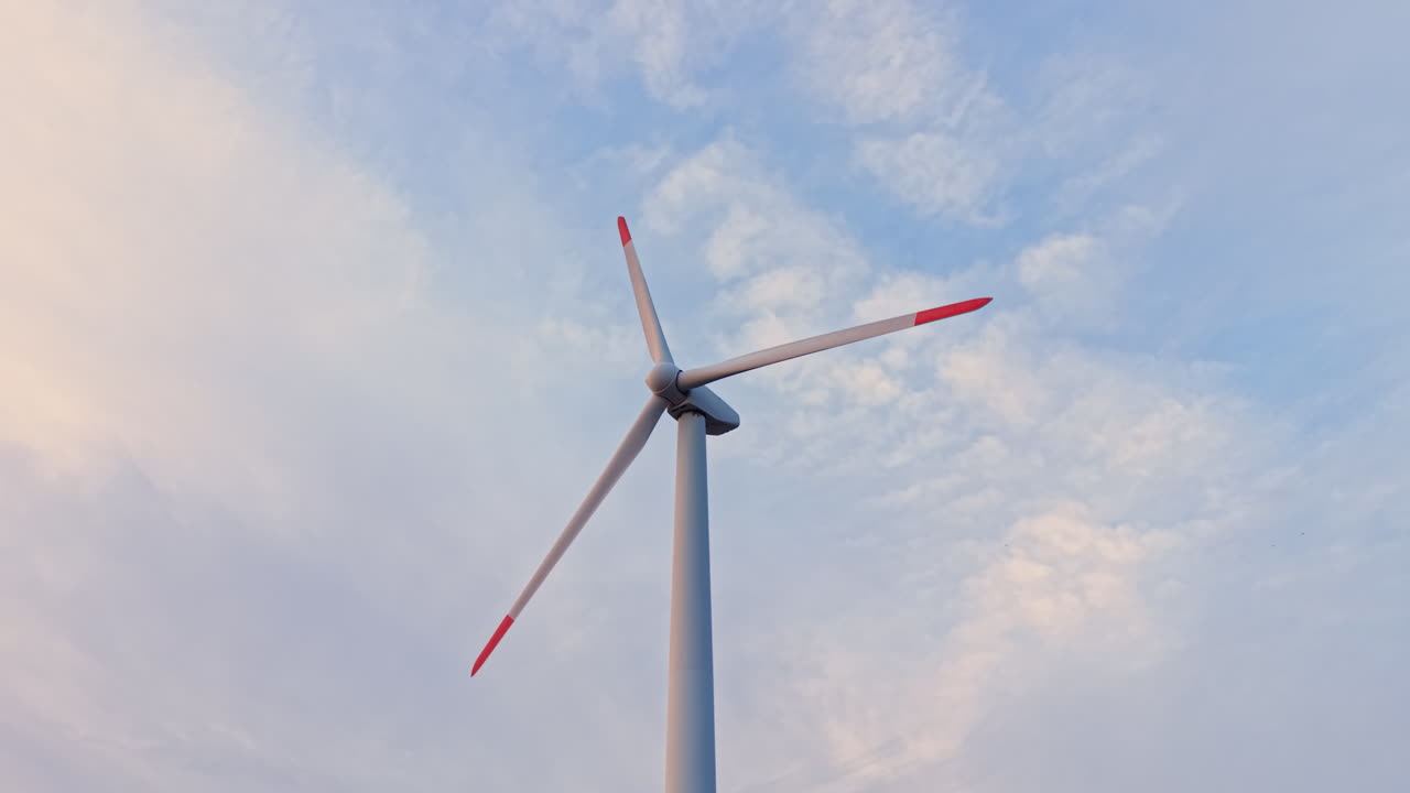 Una turbina eolica si erge imponente contro il cielo di giorno, mostrando le sue pale che girano nel vento per la produzione di energia pulita.