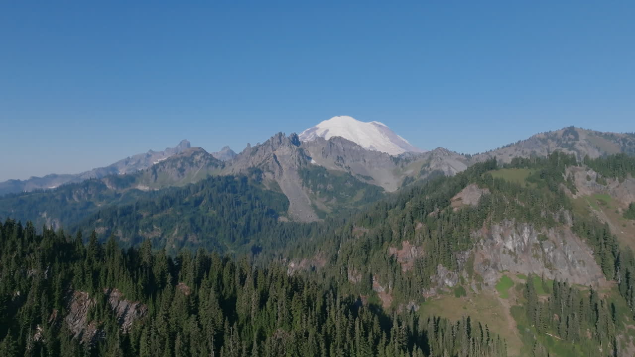 imágenes aéreas que vuelan sobre las colinas cubiertas de pinos de las montañas cascade con el monte rainier en el fondo
