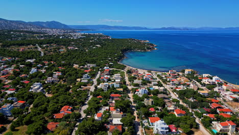 drone shot of a greek village on an island on a sunny day, with mountains on the background