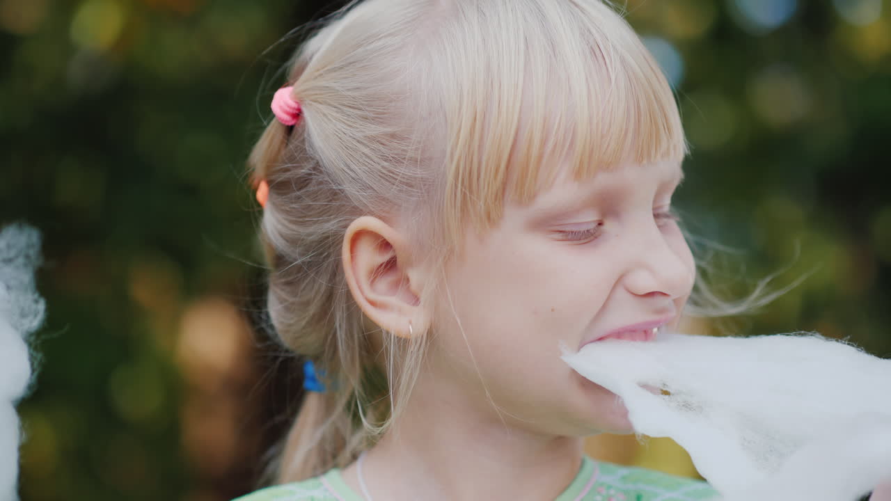 девушка ест вкусную сладкую вату в парке облизывает пальцы 4k видео