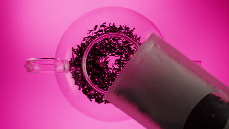 pouring loose leaf tea into a glass teapot