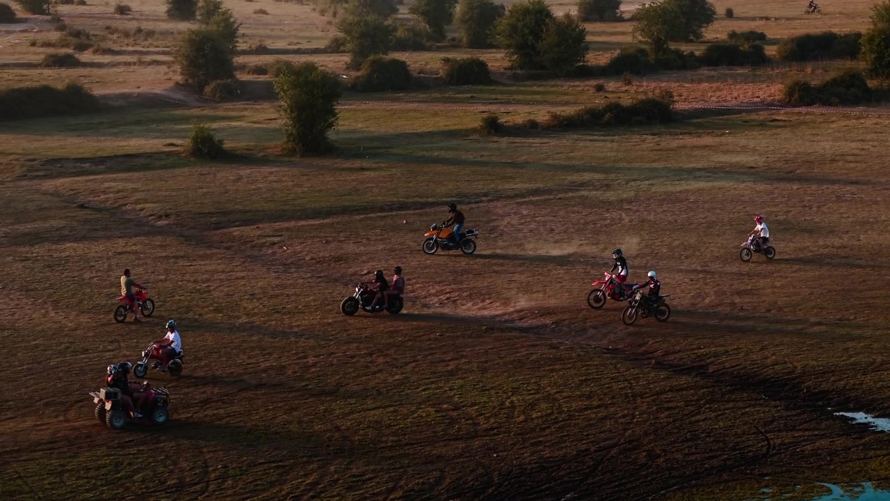 Gruppo di motociclisti che attraversano un campo aperto vicino a un lago