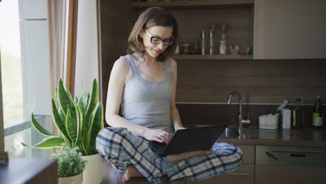 Young-woman-sitting-on-table-using-laptop