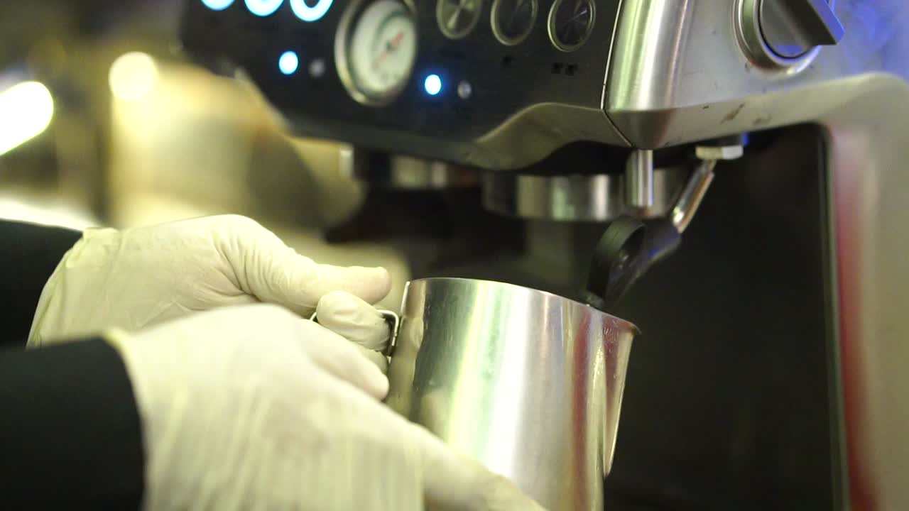 vista cercana del soporte de la máquina de café llenando una taza de metal con leche caliente