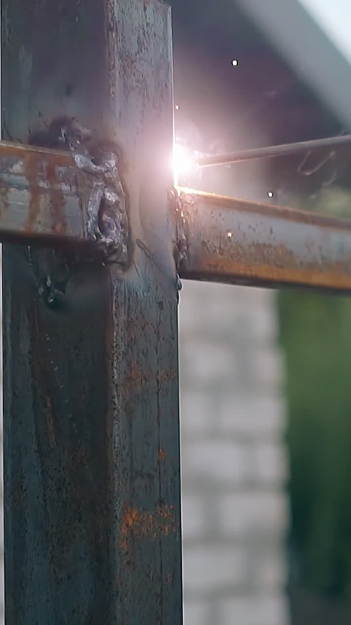 slow motion close view builder connects details of country house fence with welding instrument in yard