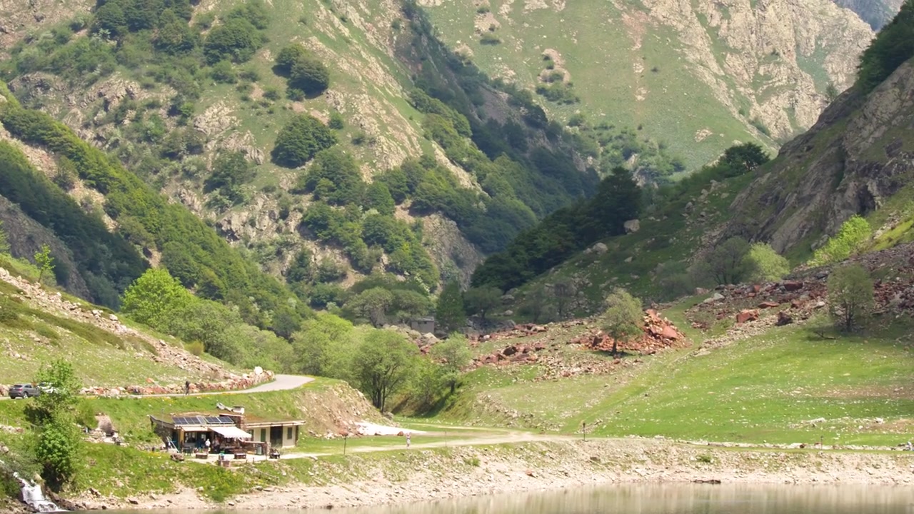Laajakuva alppijärven rannoista ja vihreistä vuorenrinteistä Lago della Rovinassa, Italiassa