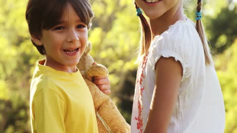 niño y niña de pie juntos con bolsa y juguete suave