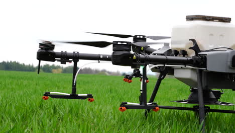 y el lanzamiento de drones agrícolas con pulverizadores en tierras de cultivo verdes, desde cerca