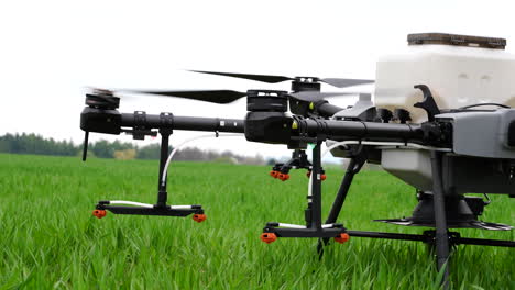 starting and launching agriculture drone with sprayers on green farming land, close up