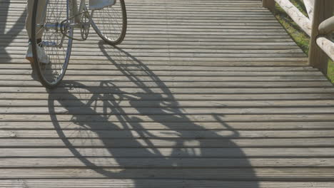 shadow of cyclist and bike on a sunny boardwalk