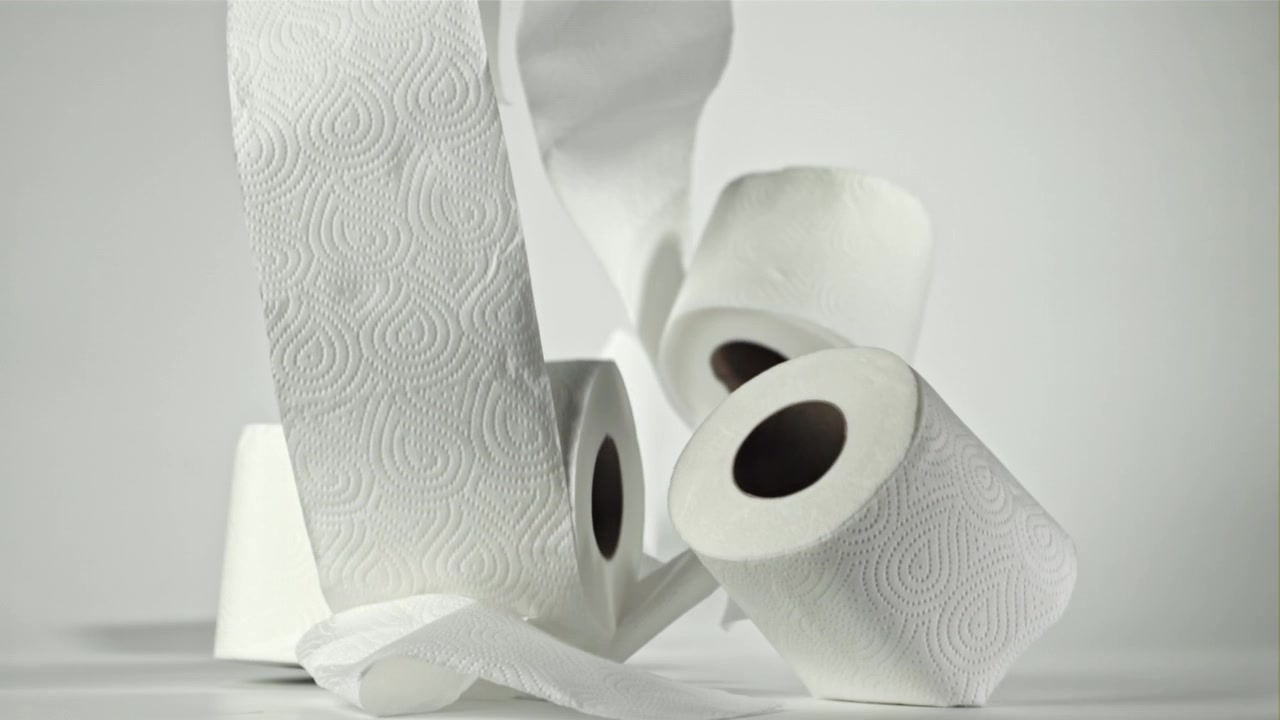 Many rolls of toilet paper falling and scattering on a white background