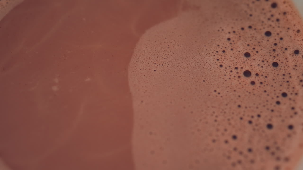 Cinematic shot of a boat propeller near a red hull, reflecting vibrant colors on the water surface