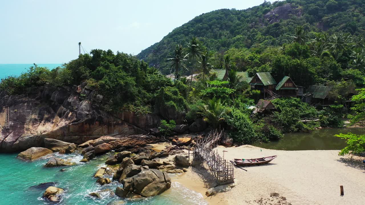 Fishing boat and a wooden deck on the Haad Than Sadet Beach, Koh Phangan, Thailand during the low tide
