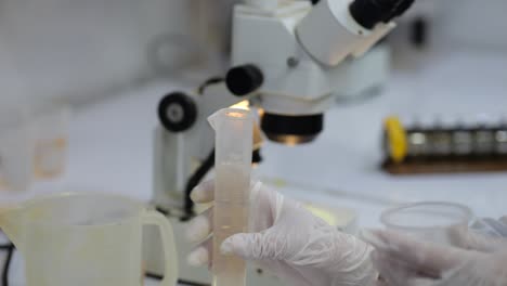 scientist pouring water sample from test tube to water cup, lab analysis