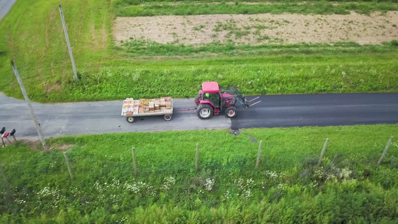 Tractor pulling a wagon of produce on a rural road