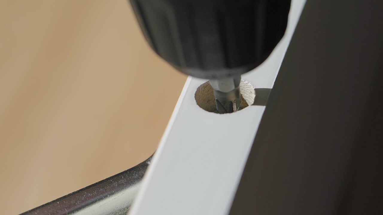 perforación de un tornillo en una parte de muebles de madera blanca