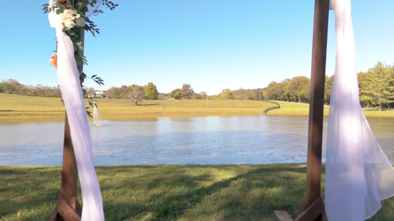 Dolly forward toward a dreamy wedding arch—white drapes flutter, flowers bloom, and the aisle whispers promises in the quiet before “I do.”
