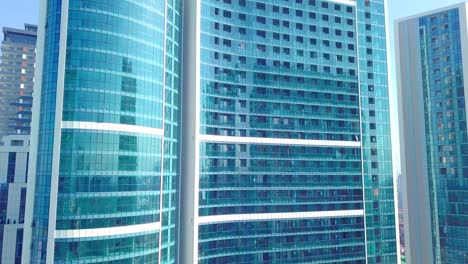 shot of reflections of sun, clouds and sky on glass windows of city skyscraper.