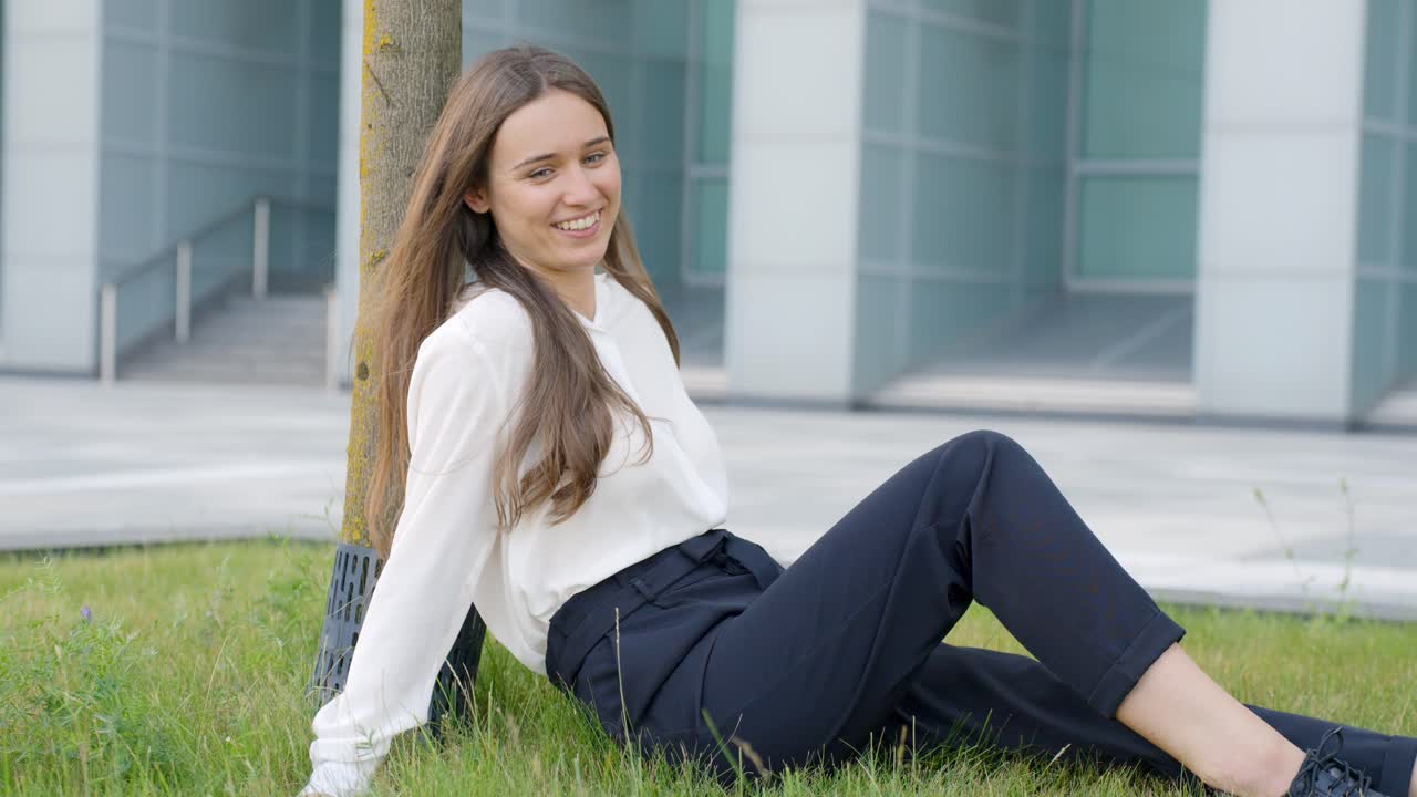 Chica báltica morena relajándose en la hierba, descanso de oficina, en cámara lenta.