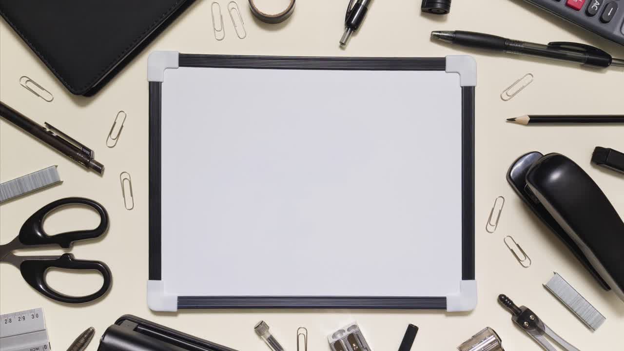 Monochrome stationery arranges around a whiteboard in stop motion with copy space on a light background