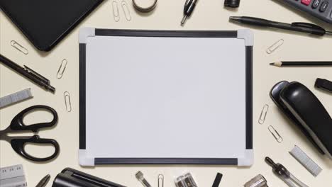 monochrome stationery arranges around a whiteboard in stop motion with copy space on a light background
