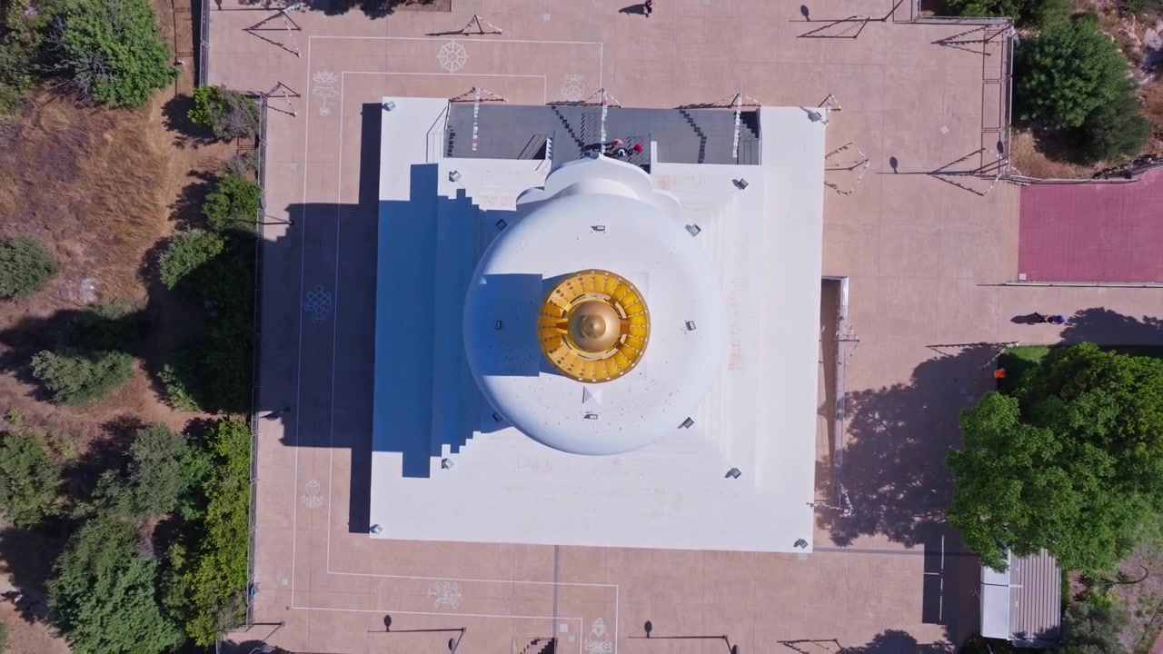 Riprese con drone della Stupa di Benalmádena, Andalusia, scattate direttamente dall'alto a mezzogiorno d'estate, rivelando la cupola dorata, le terrazze bianche e la circostante collina arida