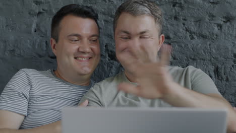happy gay couple watching laptop
