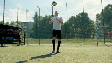 a young soccer man training freestyle tricks with the ball on a street football pitch on a sunny day 7