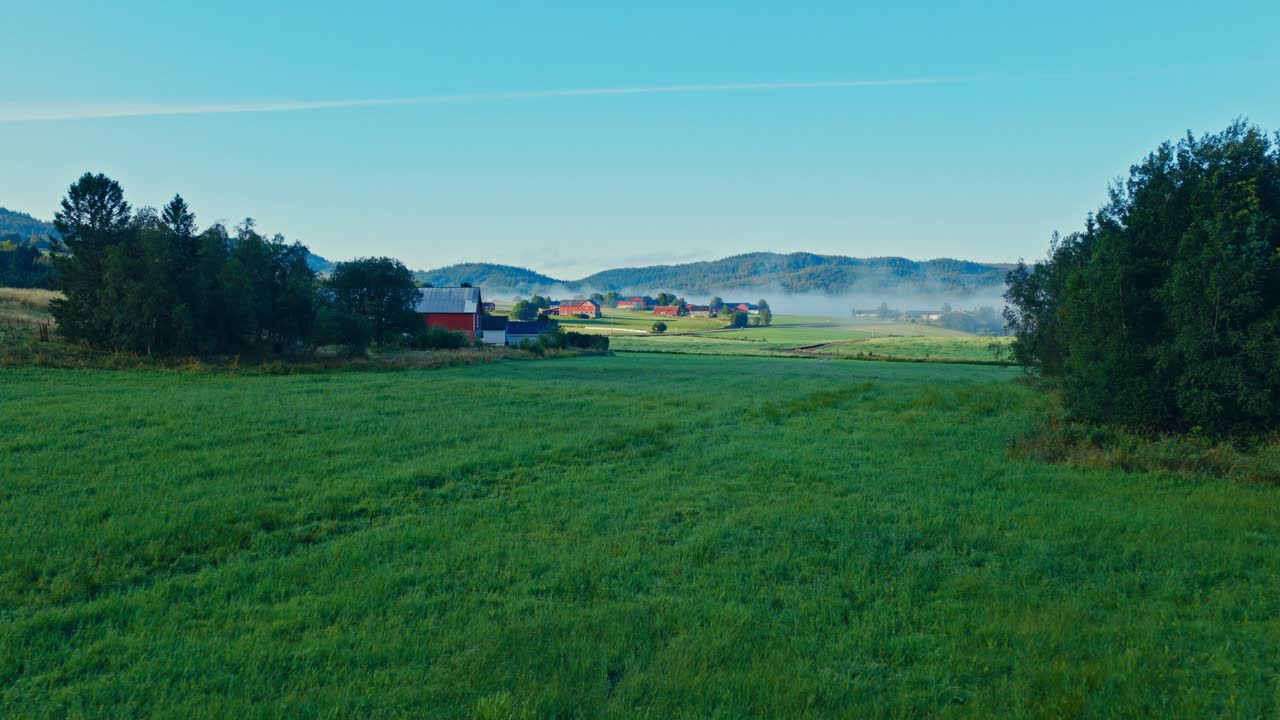 Venkovská vesnice obklopená poli a zvlněnými kopci v Norsku. Letecký záběr.