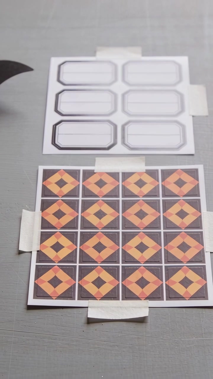 Vertical video: Panning camera shifting on gray desk showing label and tile sheets with white tape