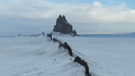 4k aerial tracking shot of shiprock monument, covered in snow, in new mexico, usa