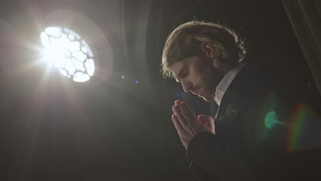 young handsome caucasian man praying in gothic church