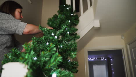 woman decorating her home with lighted garland for the christmas season